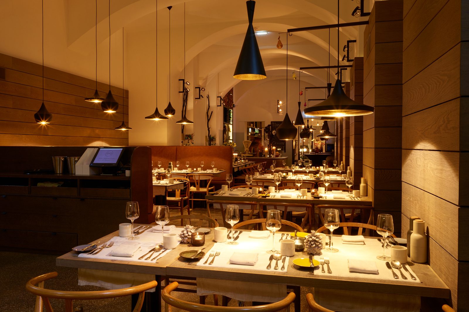 The restaurant in December: tables laid under the vault, candles and pine cones on the table