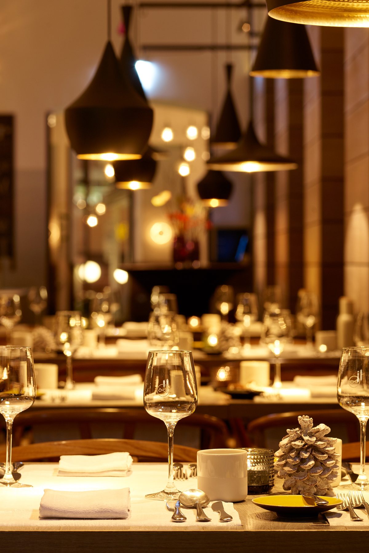 Glasses on a festively laid table, the lights of the restaurant behind